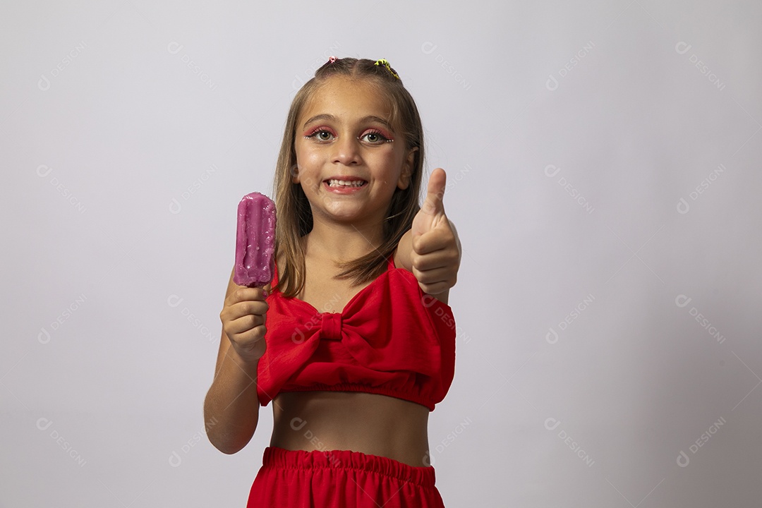 Linda menina com look vermelho segurando picolé sobre fundo de studio isolado