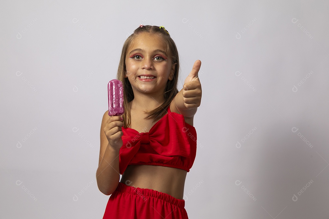 Linda menina com look vermelho segurando picolé sobre fundo de studio isolado