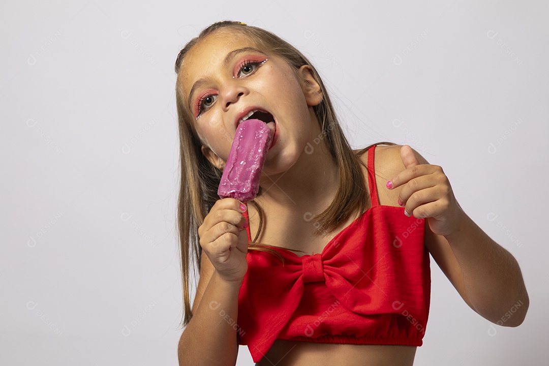 Linda menina com look vermelho segurando picolé sobre fundo de studio isolado