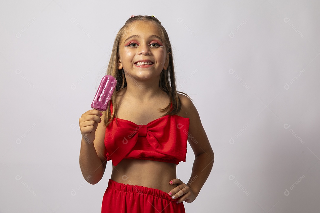Linda menina com look vermelho segurando picolé sobre fundo de studio isolado