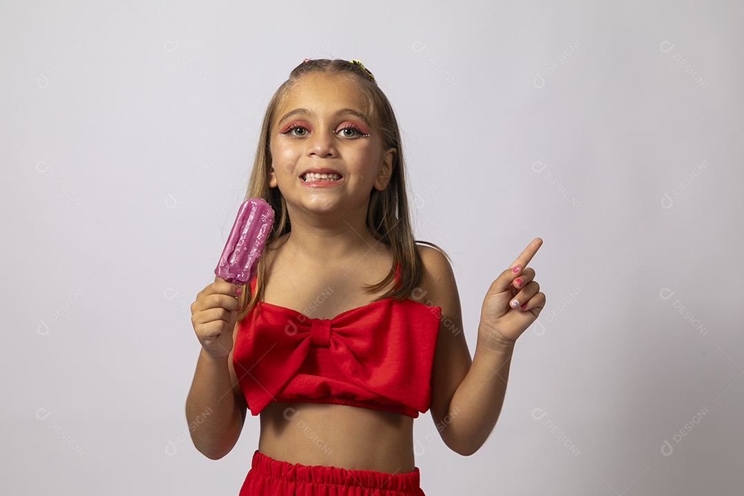 Linda menina com look vermelho segurando picolé sobre fundo de studio isolado