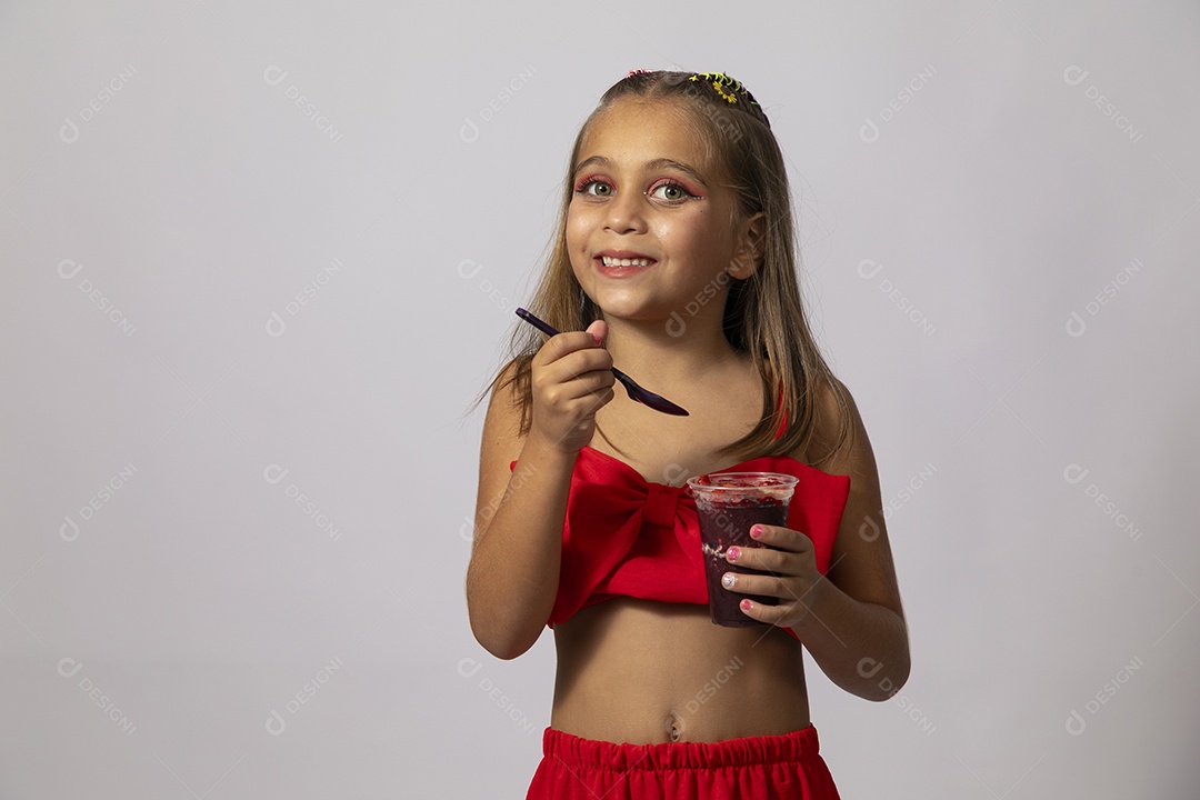 Linda menina com look vermelho segurando copo de açai sobre fundo de studio isolado