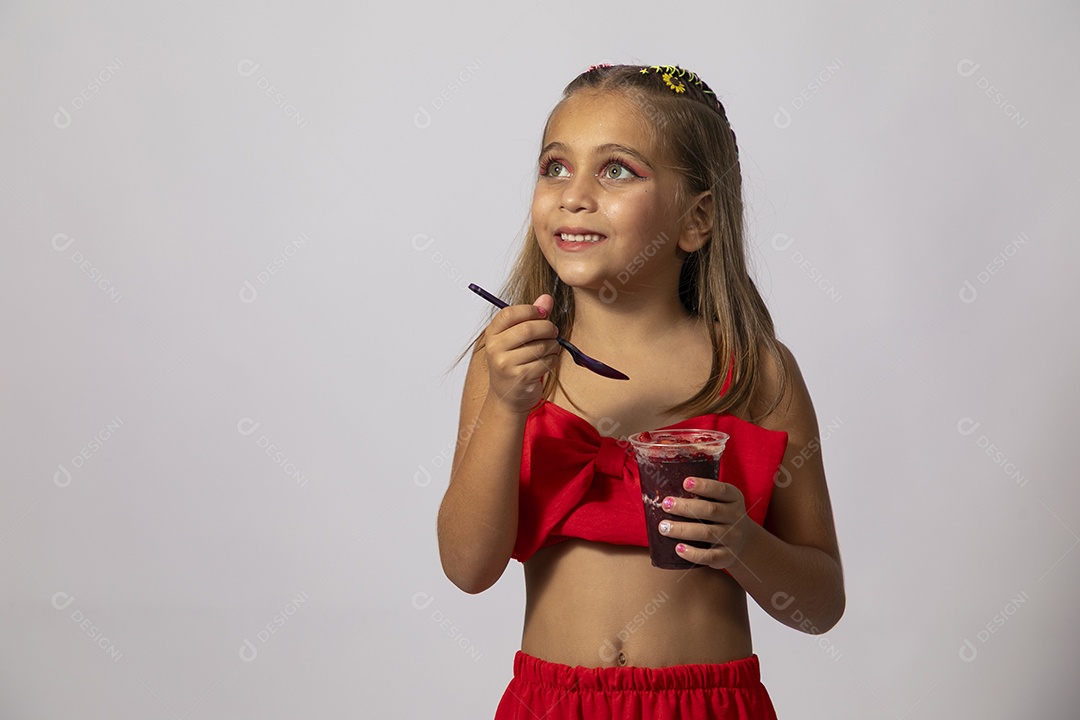Linda menina com look vermelho segurando copo de açai sobre fundo de studio isolado