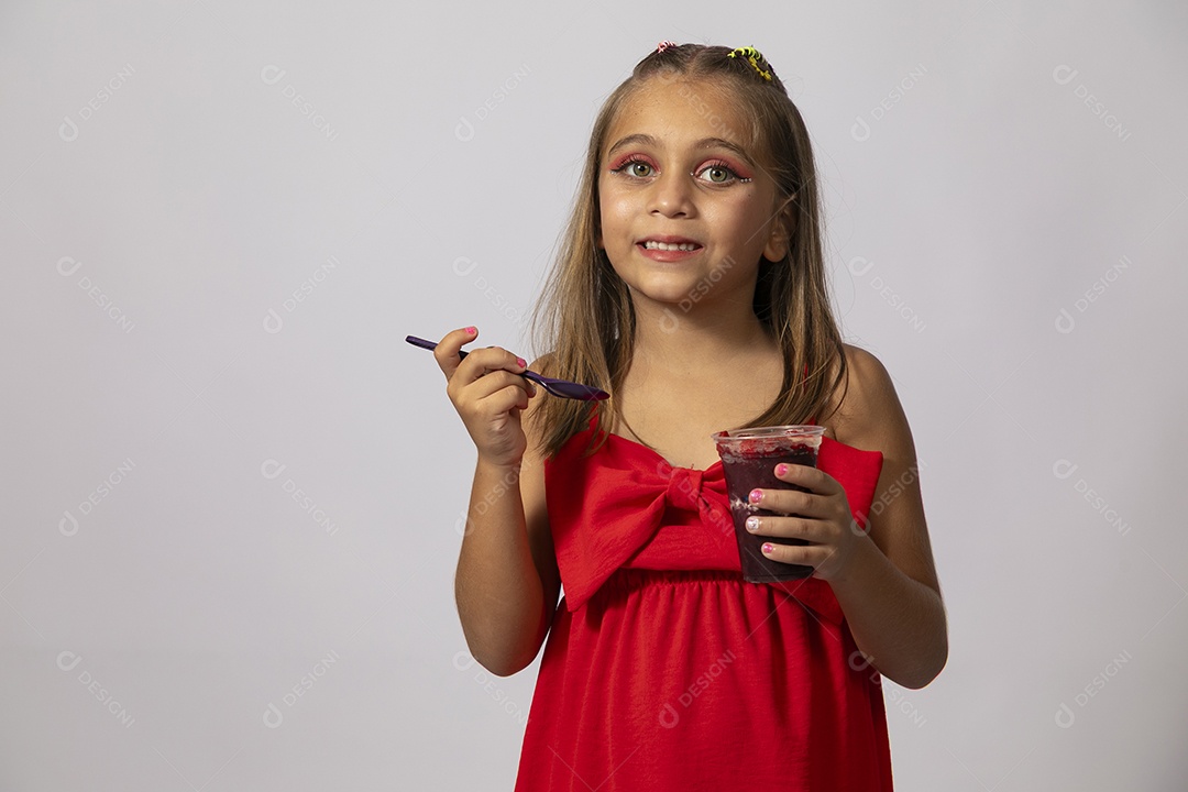 Linda menina com look vermelho segurando copo de açai sobre fundo de studio isolado