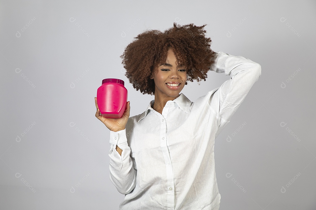 Linda mulher negra de cabelo cacheados segurando pote de creme sobre fundo branco isolado