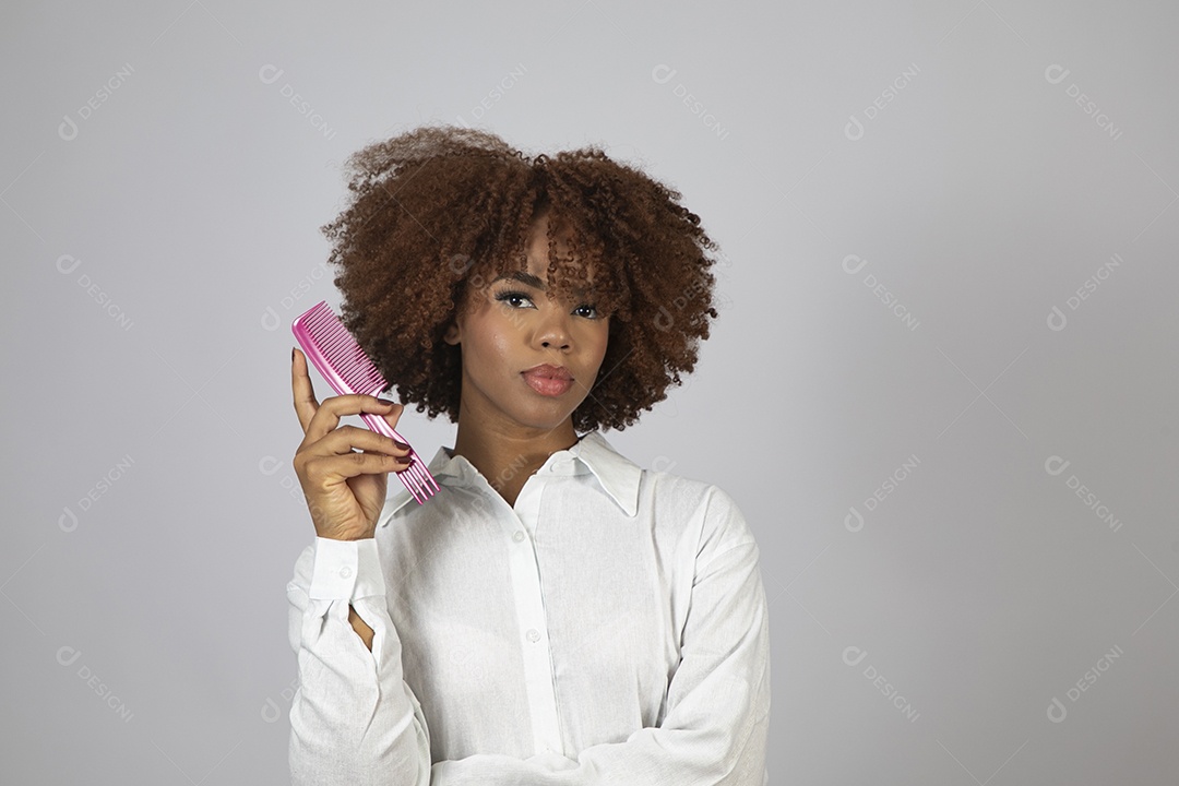 Linda mulher negra de cabelo cacheados segurando pente de plástico sobre fundo branco isolado