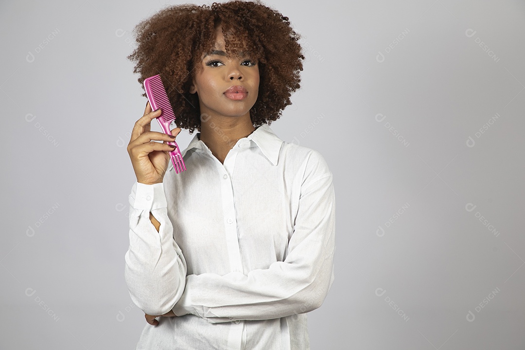 Linda mulher negra de cabelo cacheados segurando pente de plástico sobre fundo branco isolado
