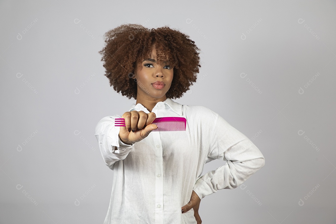Linda mulher negra de cabelo cacheados segurando pente de plástico sobre fundo branco isolado