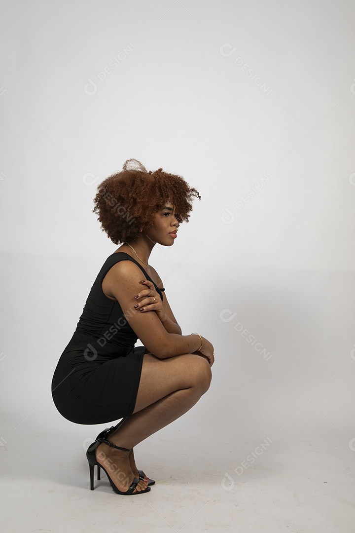 Linda mulher negra de cabelo cacheados com look preto fazendo pose sobre fundo branco isolado