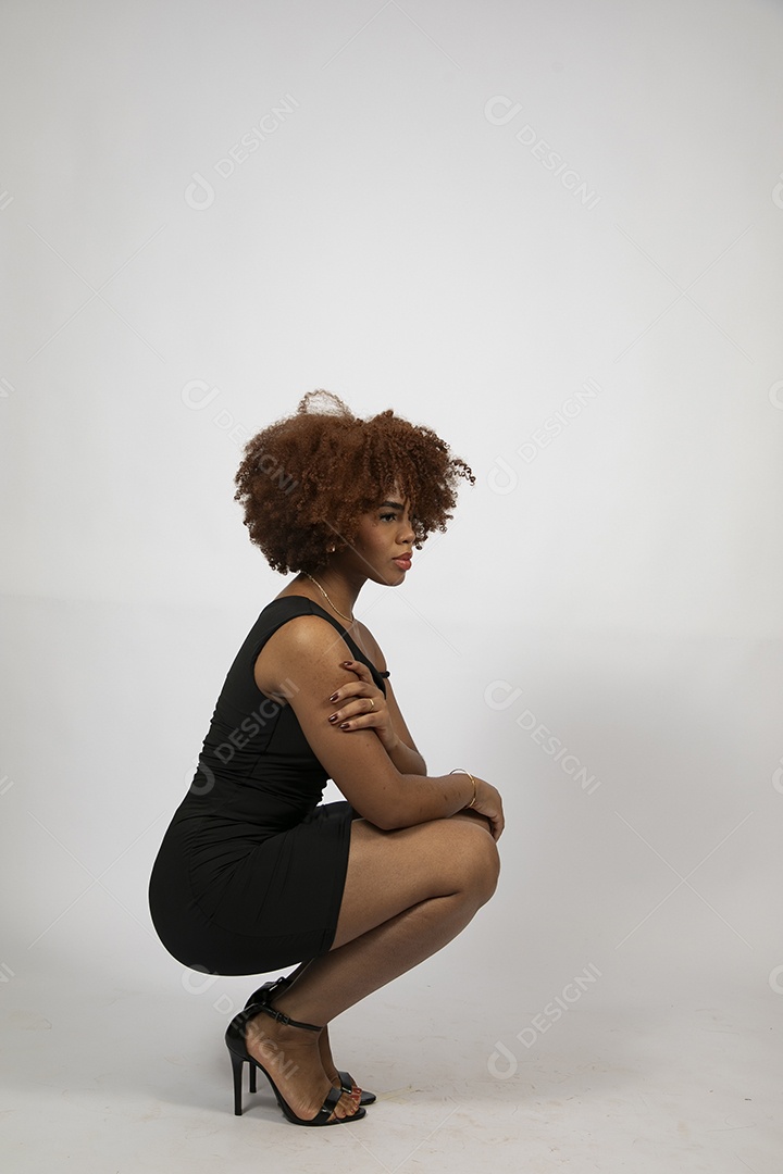 Linda mulher negra de cabelo cacheados com look preto fazendo pose sobre fundo branco isolado