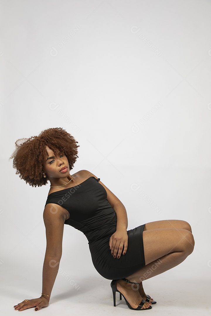 Linda mulher negra de cabelo cacheados com look preto fazendo pose sobre fundo branco isolado