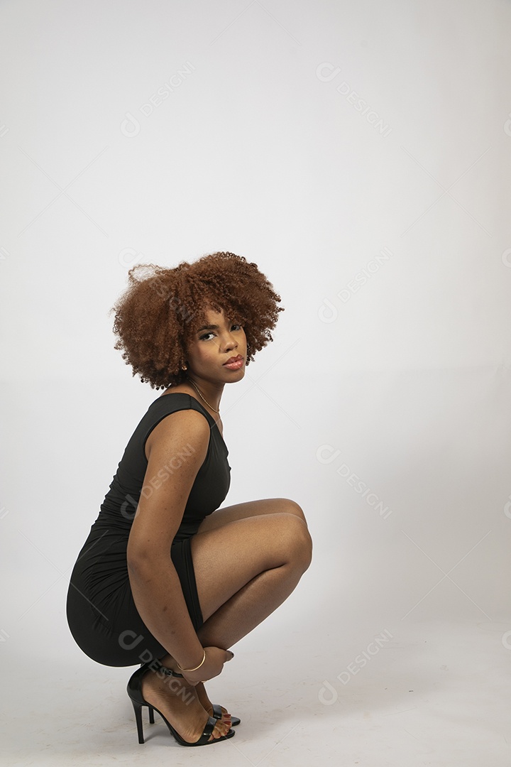 Linda mulher negra de cabelo cacheados com look preto fazendo pose sobre fundo branco isolado