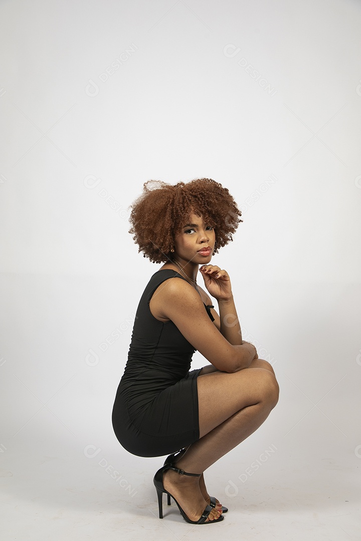 Linda mulher negra de cabelo cacheados com look preto fazendo pose sobre fundo branco isolado