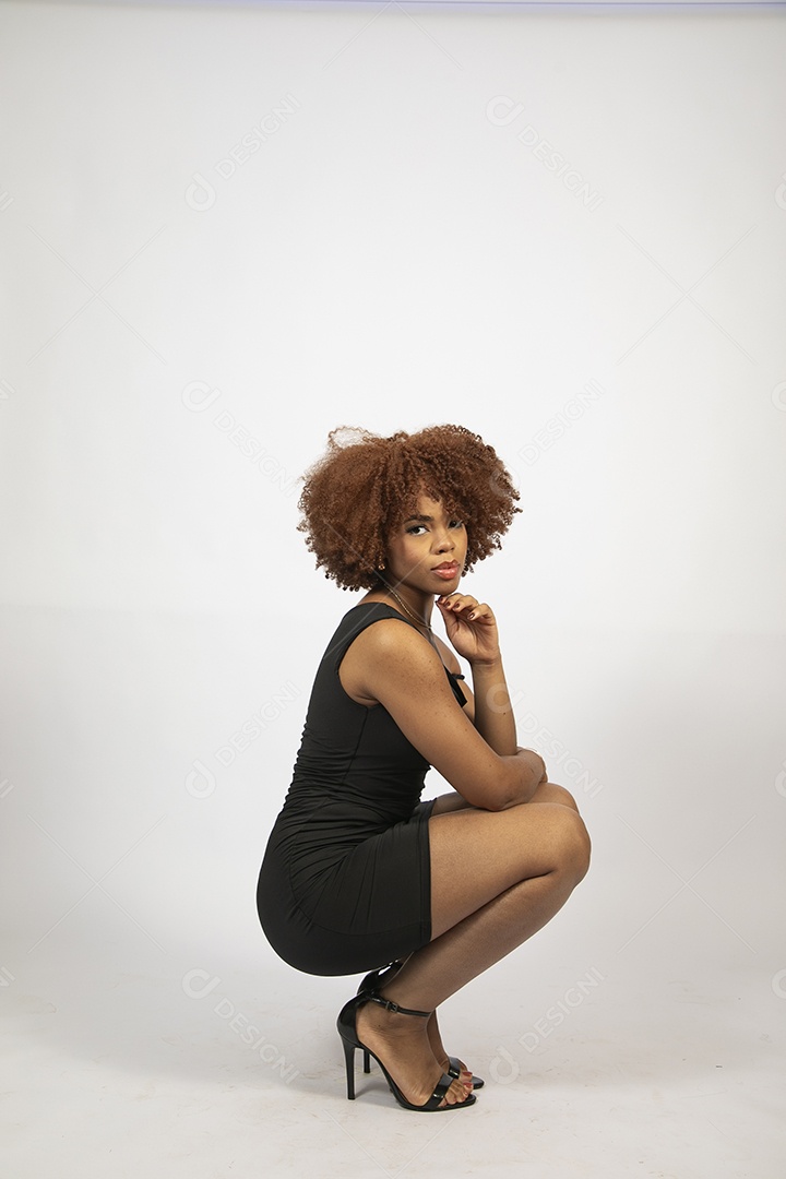 Linda mulher negra de cabelo cacheados com look preto fazendo pose sobre fundo branco isolado