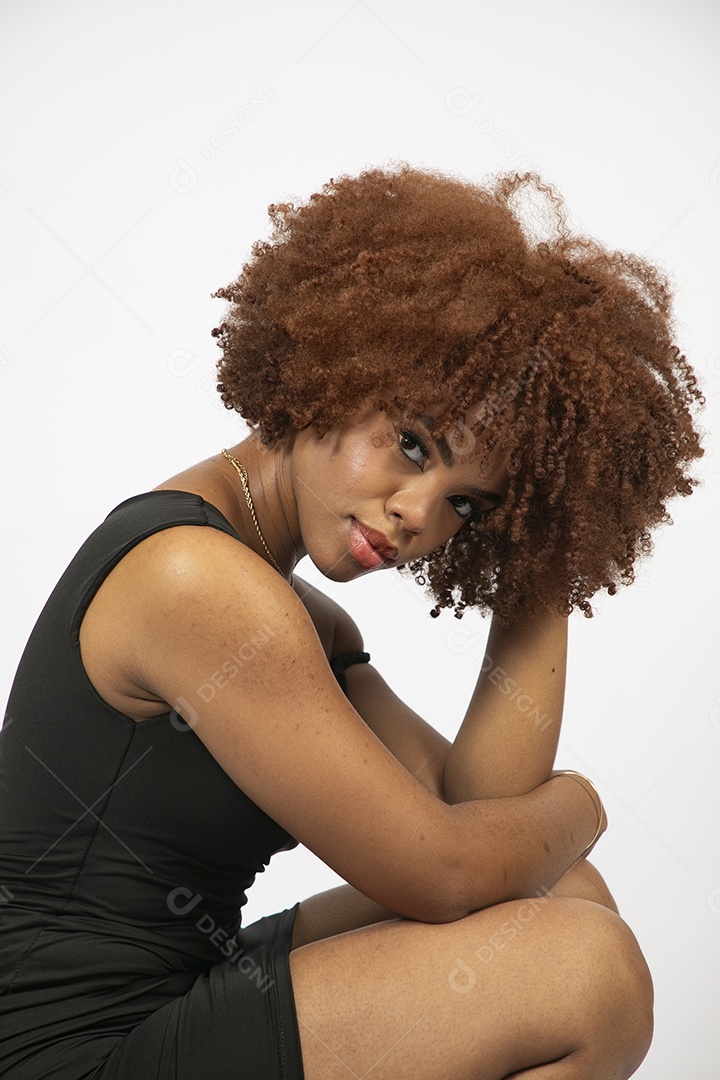 Linda mulher negra de cabelo cacheados com look preto fazendo pose sobre fundo branco isolado