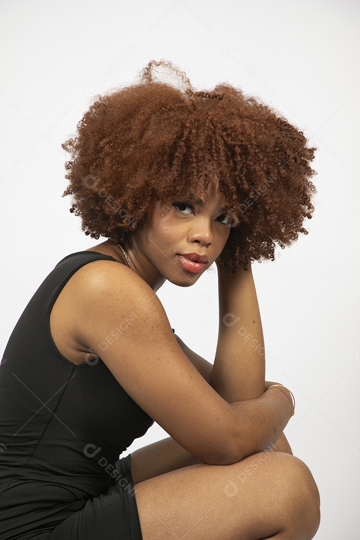 Linda mulher negra de cabelo cacheados com look preto fazendo pose sobre fundo branco isolado