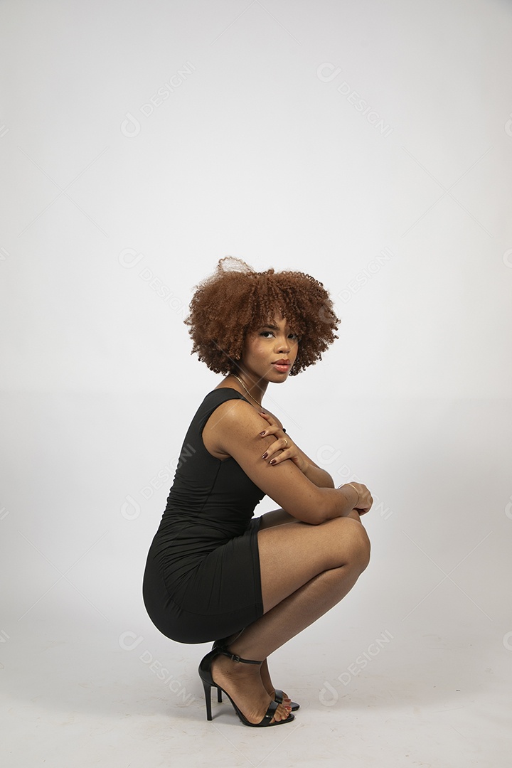 Linda mulher negra de cabelo cacheados com look preto fazendo pose sobre fundo branco isolado