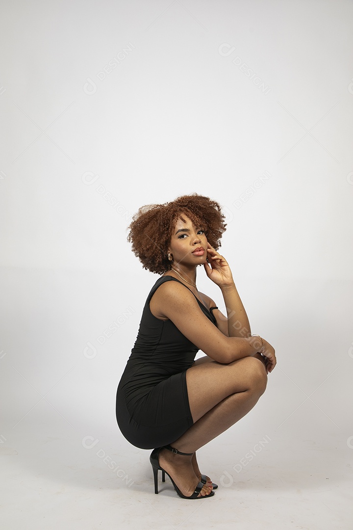 Linda mulher negra de cabelo cacheados com look preto fazendo pose sobre fundo branco isolado