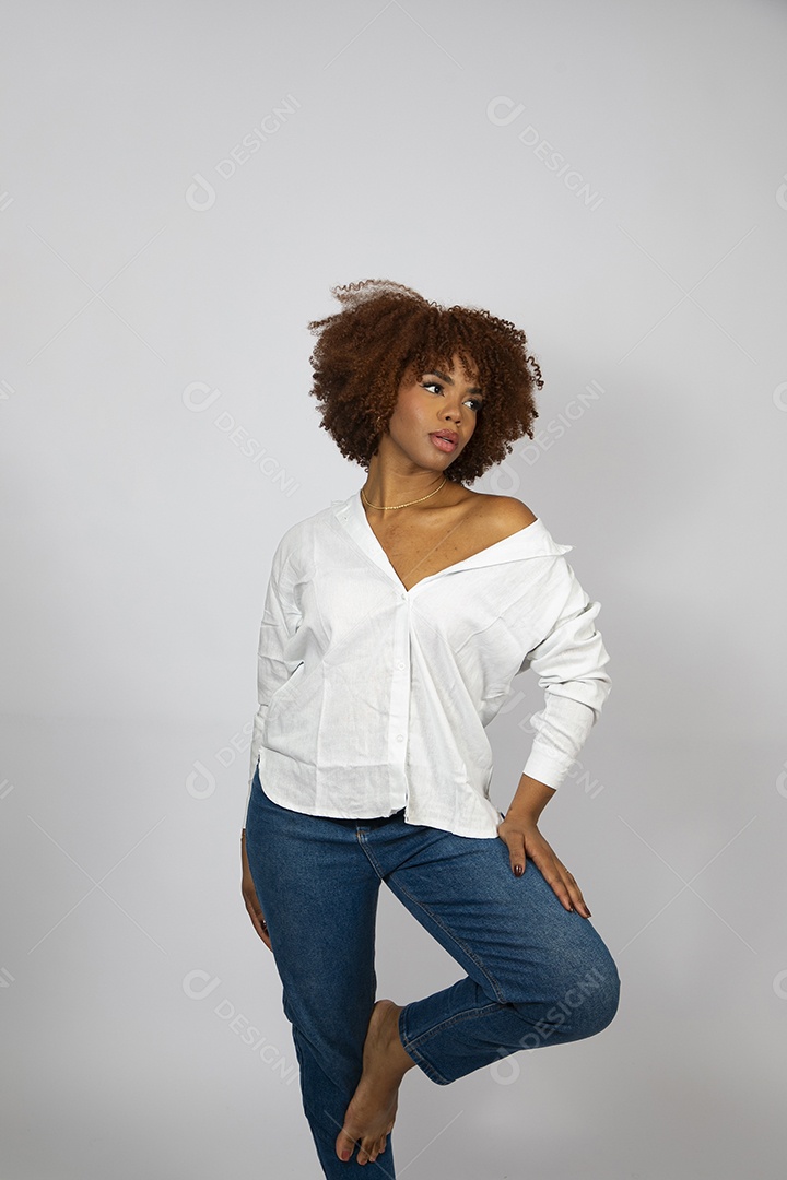 Linda mulher negra de cabelo cacheados sentada fazendo pose sobre fundo branco isolado