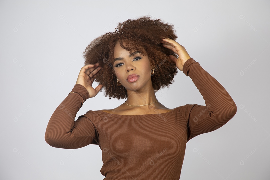 Linda mulher negra de cabelo cacheados usando vestido marrom fazendo pose sobre fundo branco isolado