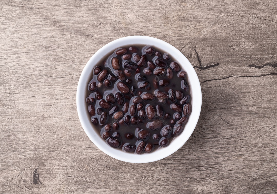 A imagem mostra uma tigela de feijão preto ou feijão vermelho cozido