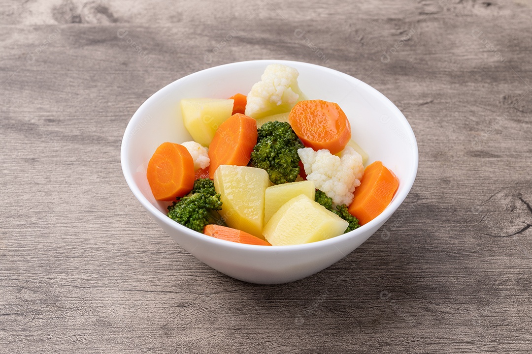 A imagem mostra uma tigela de salada de legumes cozidos no vapor, que inclui brócolis, cenoura e couve-flor