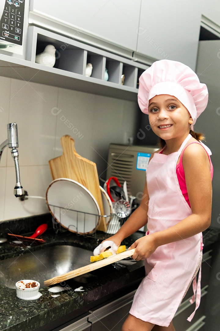 Linda garotinha usando avental e chapéu de chef de cozinha