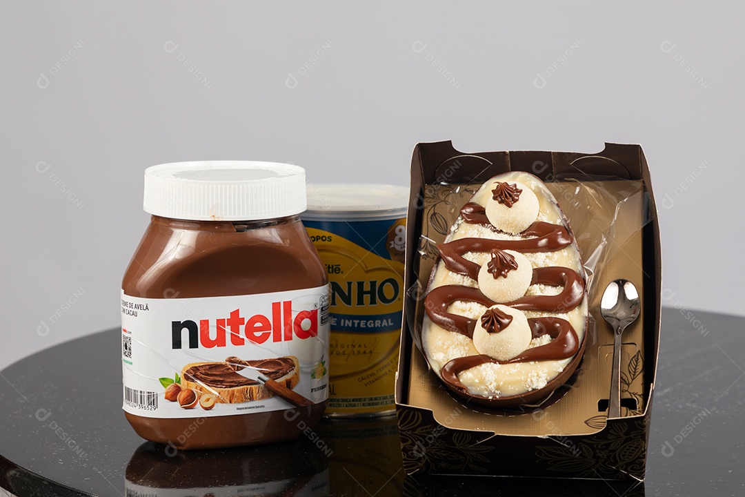 Ovo de páscoa de colher ao lado de leite ninho e nutella sobre uma mesa