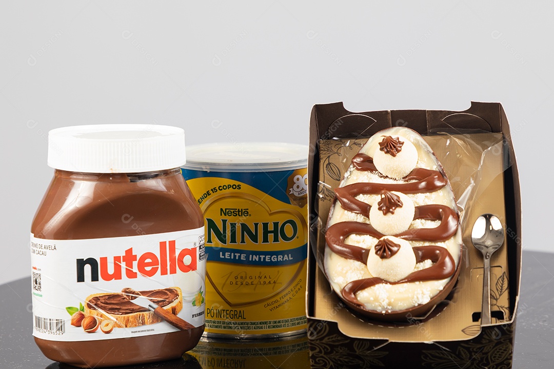 Ovo de páscoa de colher ao lado de leite ninho e nutella sobre uma mesa