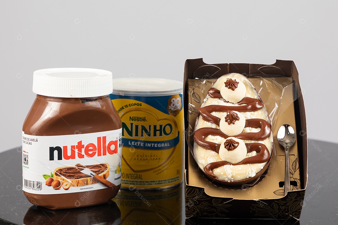 Ovo de páscoa de colher ao lado de leite ninho e nutella sobre uma mesa