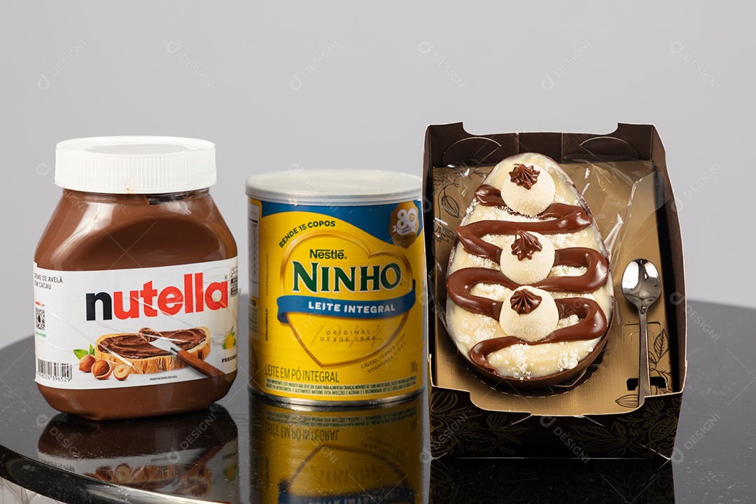 Ovo de páscoa de colher ao lado de leite ninho e nutella sobre uma mesa