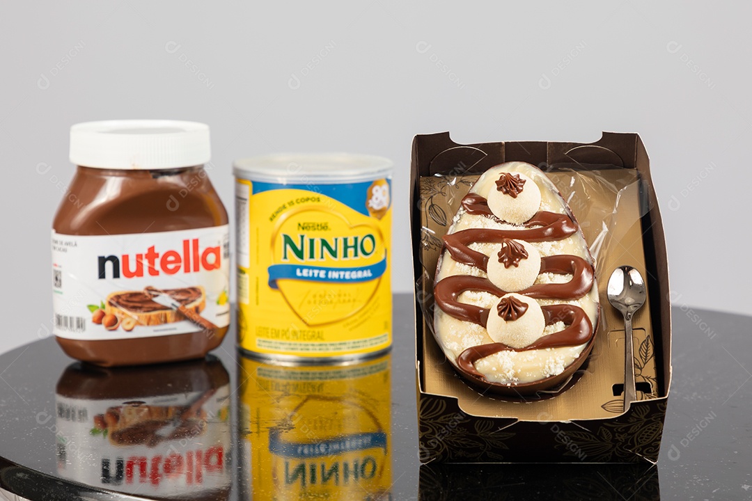 Ovo de páscoa de colher ao lado de leite ninho e nutella sobre uma mesa