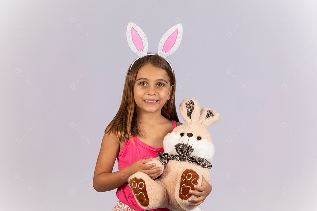 Linda garotinha usando tiara e segurando coelho de pelúcia celebrando páscoa