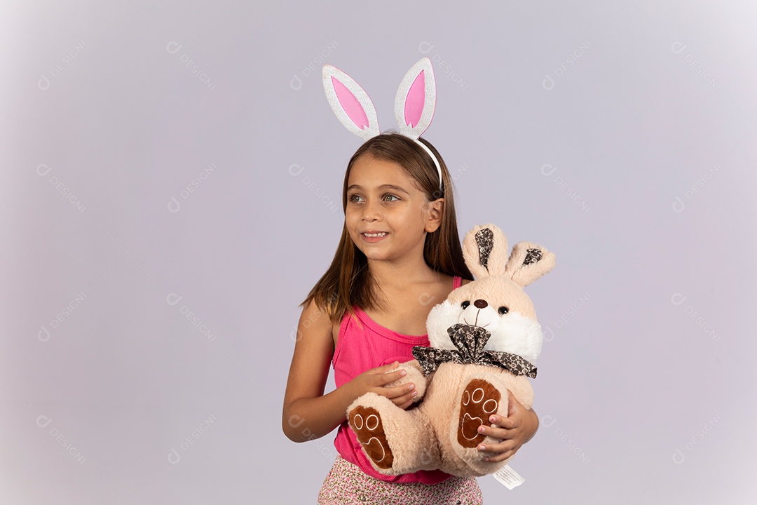 Linda garotinha usando tiara e coelho de pelúcia celebrando páscoa