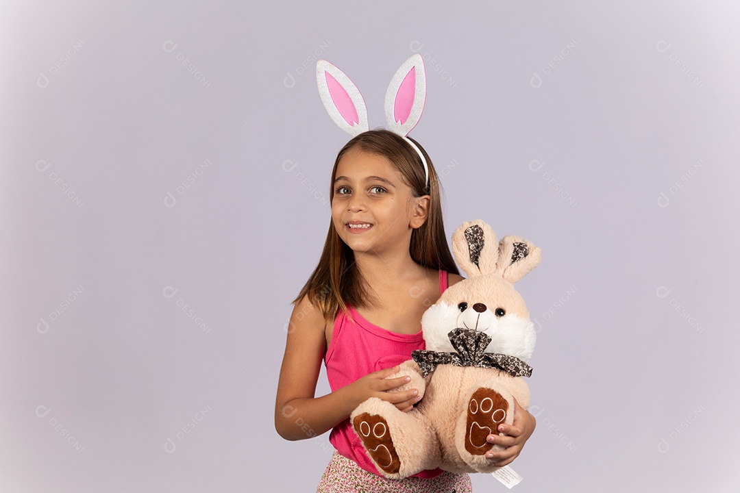 Linda garotinha usando tiara e coelho de pelúcia celebrando páscoa
