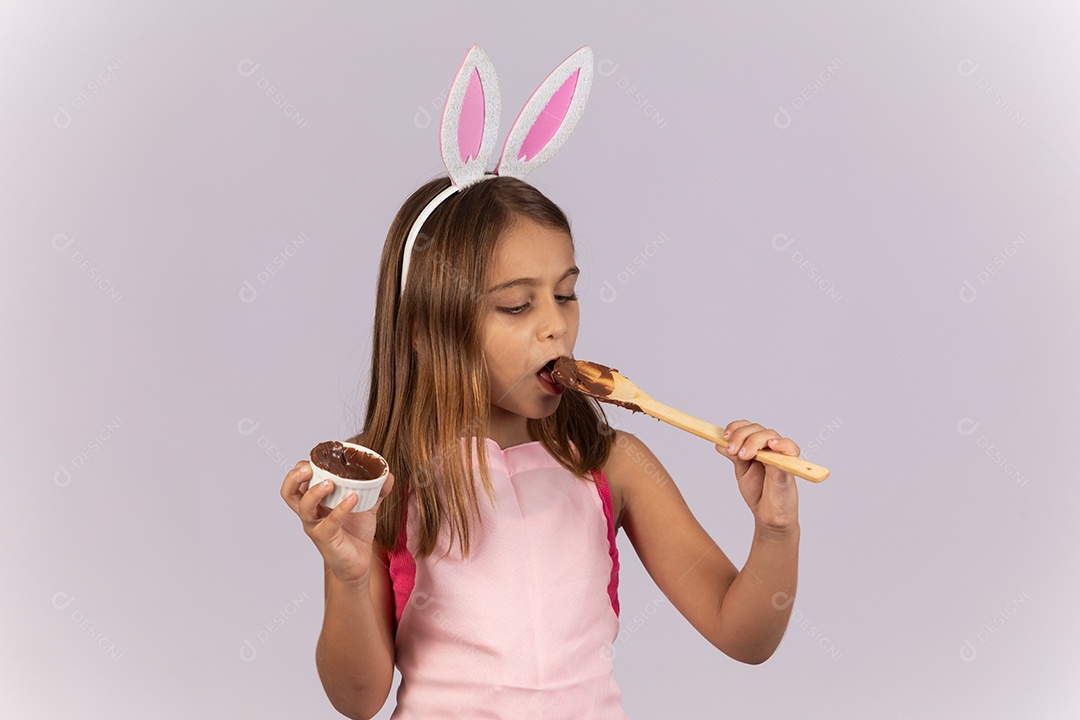Linda garotinha comendo ovo de chocolate celebrando páscoa