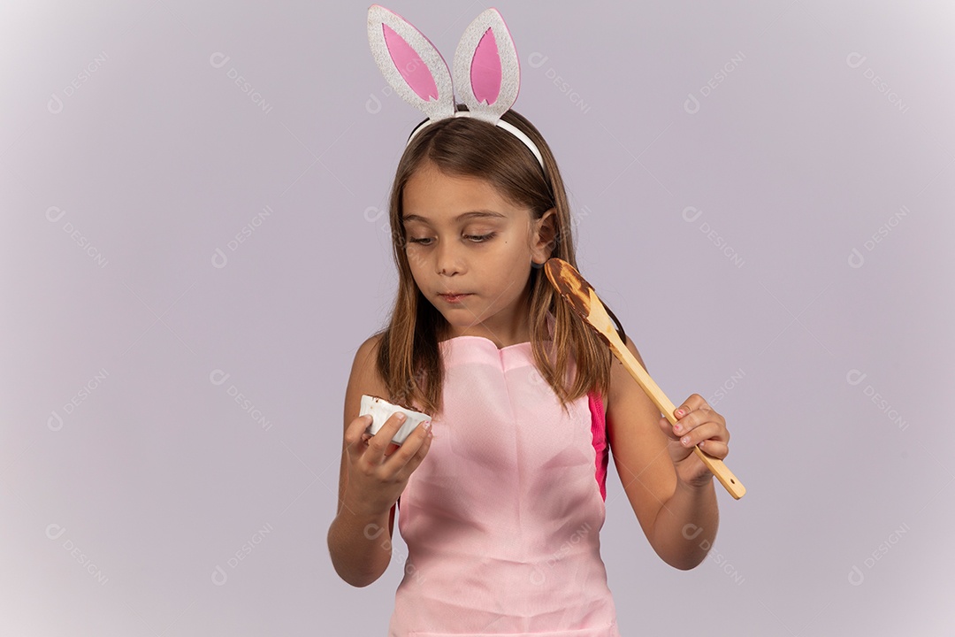 Linda garotinha comendo ovo de chocolate celebrando páscoa