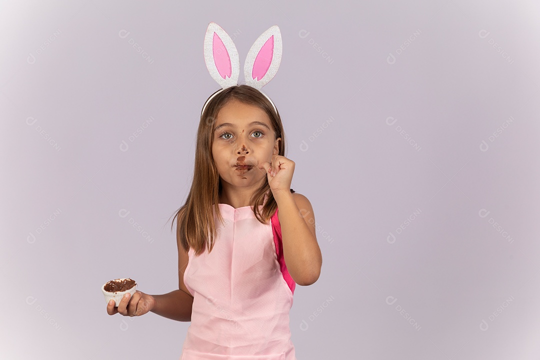 Linda garotinha comendo ovo de chocolate celebrando páscoa