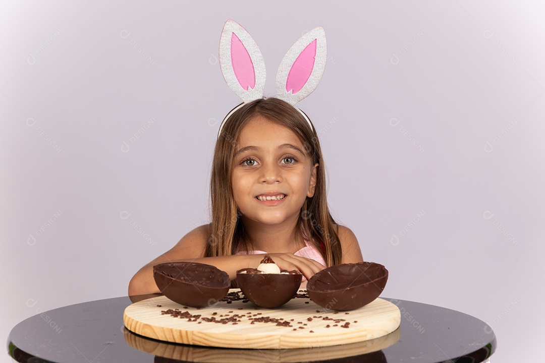 Linda garotinha comendo ovo de chocolate celebrando páscoa