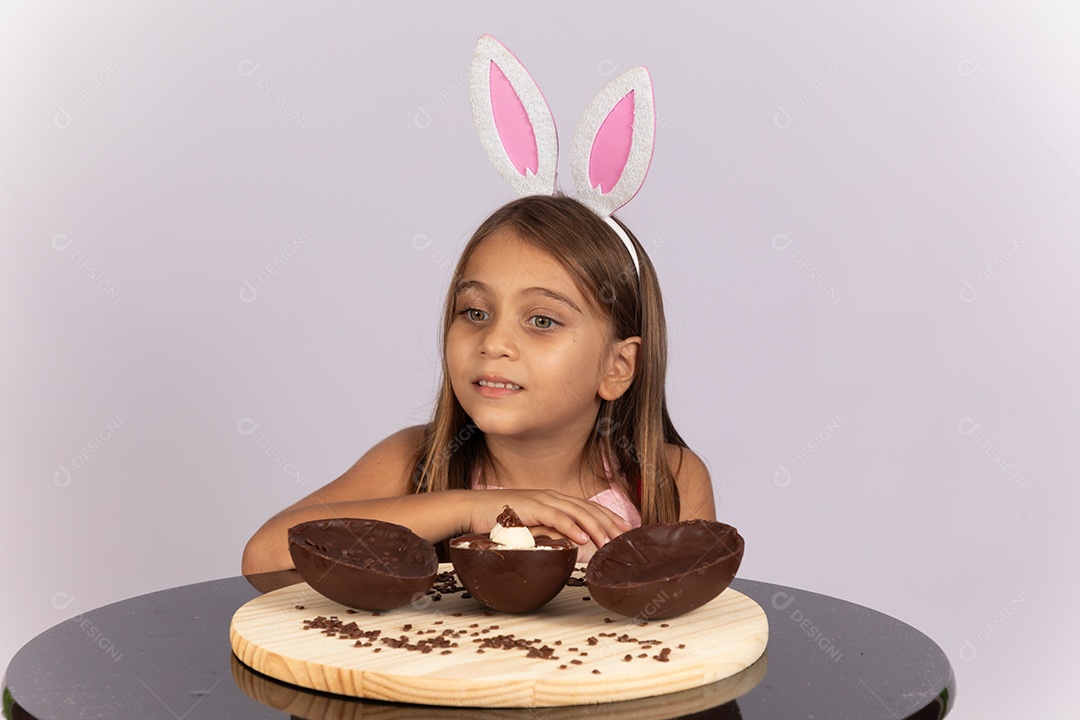 Linda garotinha comendo ovo de chocolate celebrando páscoa