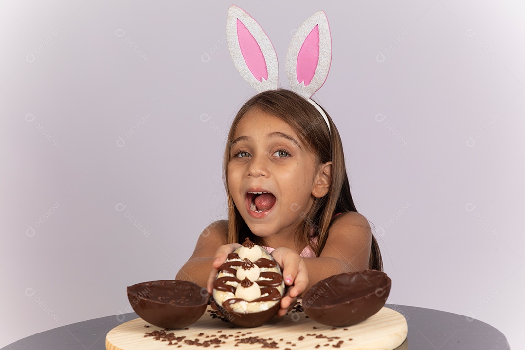 Linda garotinha comendo ovo de chocolate celebrando páscoa