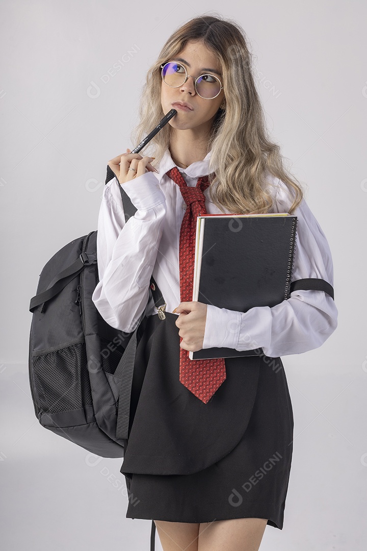 Jovem estudante com roupa escolar e livros nas mãos