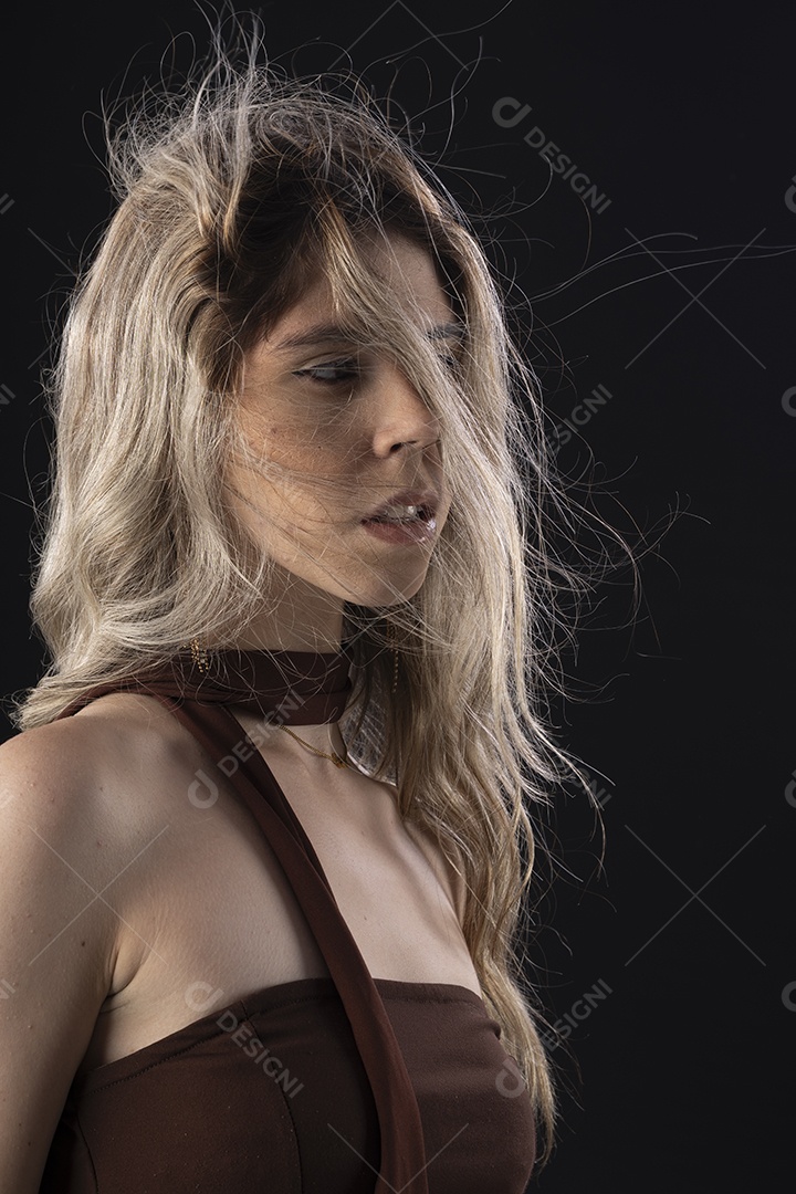 Jovem loira usando um vestido luxuoso em um fundo preto