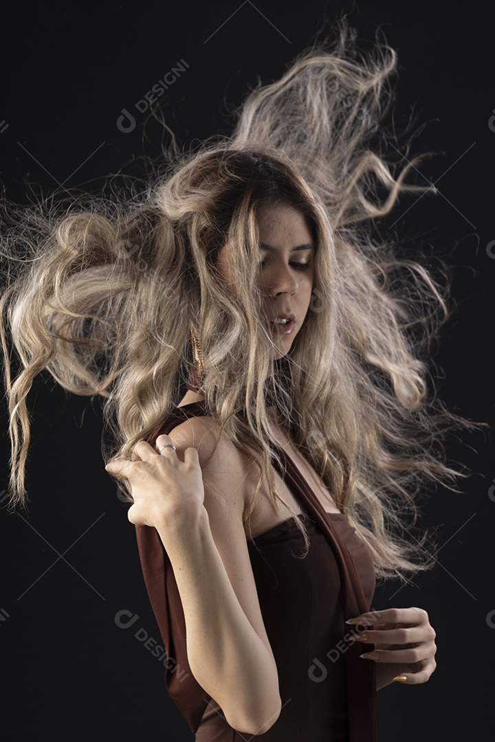 Jovem loira usando um vestido luxuoso em um fundo preto