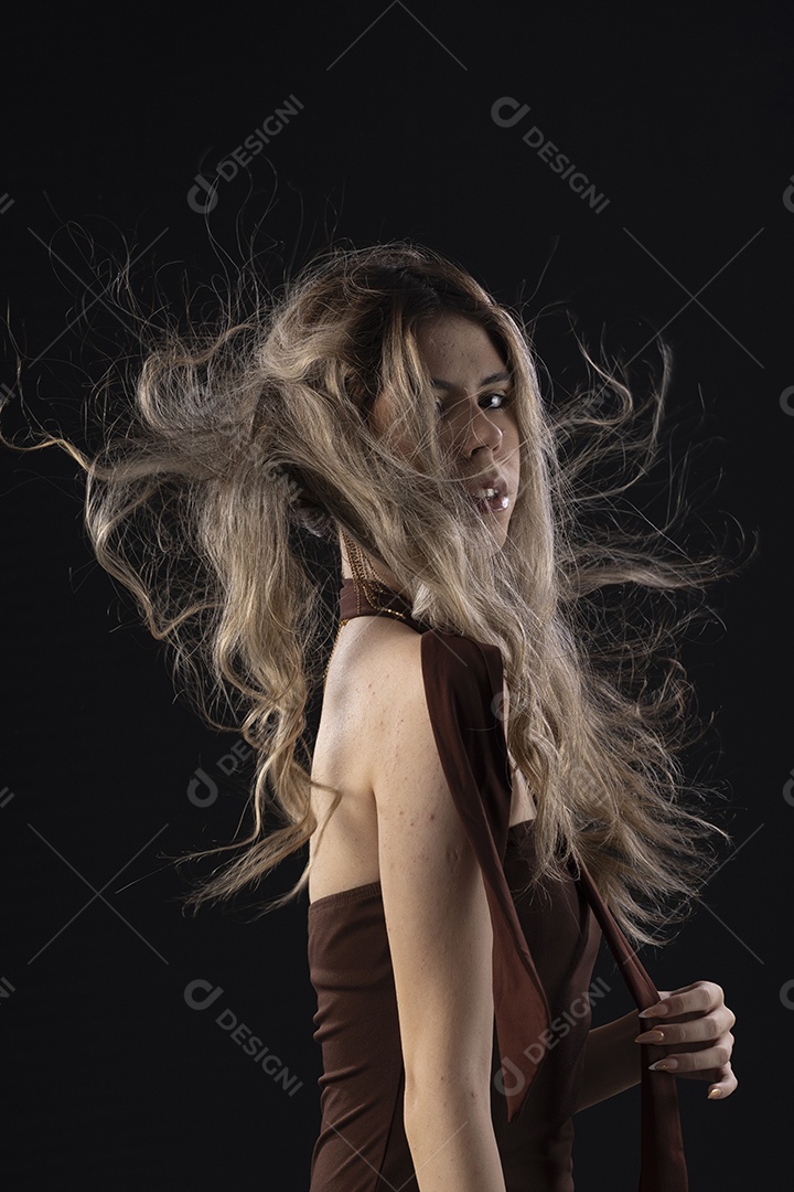 Jovem loira usando um vestido luxuoso em um fundo preto