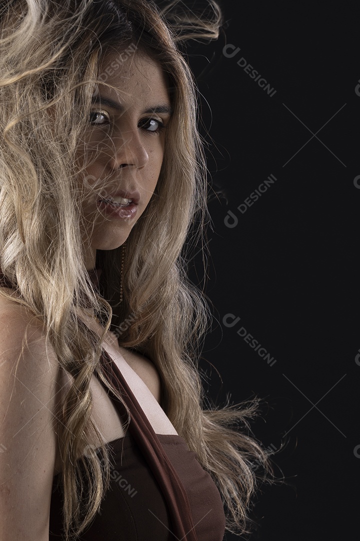 Jovem loira usando um vestido luxuoso em um fundo preto