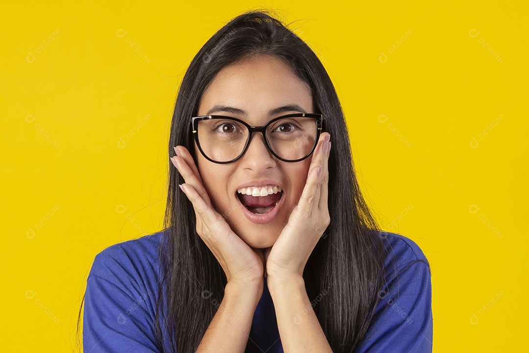 Jovem brasileira usando óculos e camisa azul em um estúdio com fundo amarelo