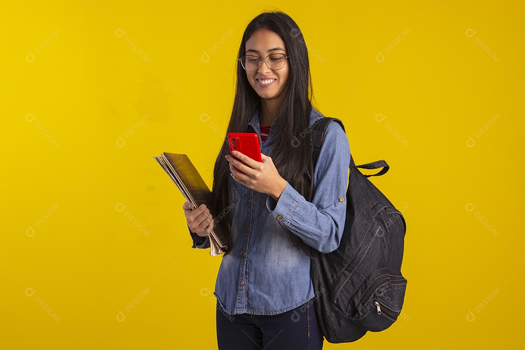 Jovem estudante com livros e celular na mão