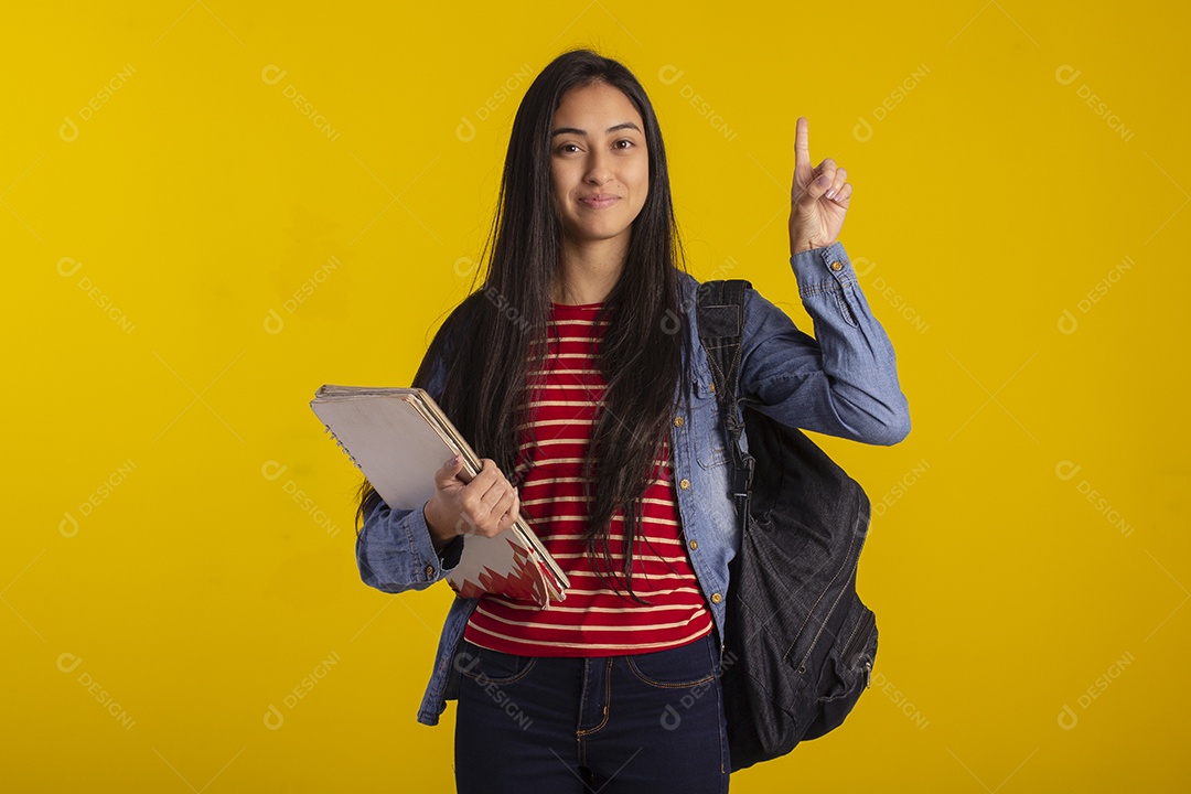 Estudante linda com livros nas mãos e apontando para cima