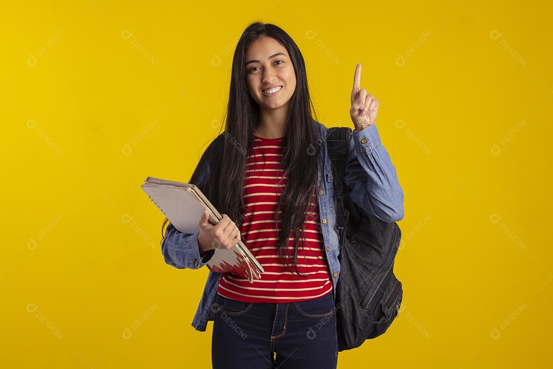 Estudante linda com livros nas mãos e apontando para cima